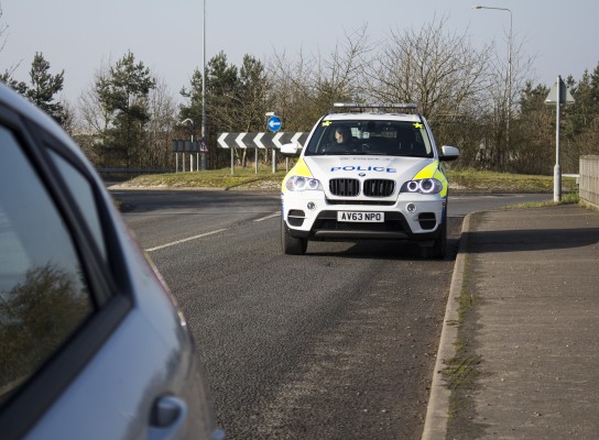 Police vehicle pulling a car over on a main road