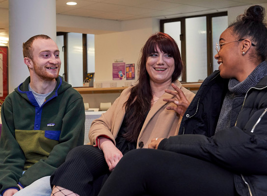 Three students chatting on a sofa