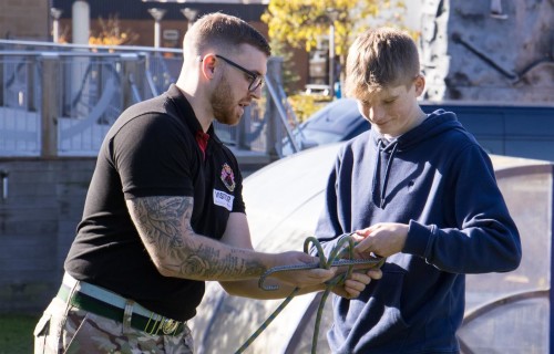 A member of the Army Outreach team demonstrating a rope knot to Uniformed Services student Sam Frost