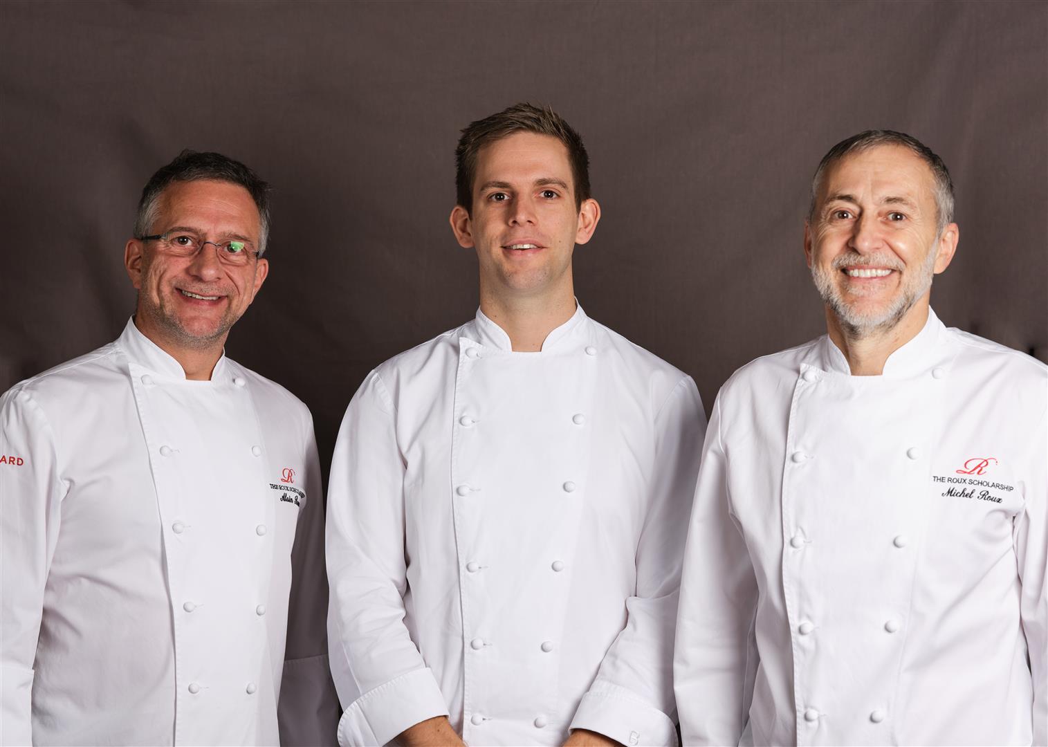 Oli Williamson wearing chef whites and posing with Alain Roux and Michel Roux Jr Large